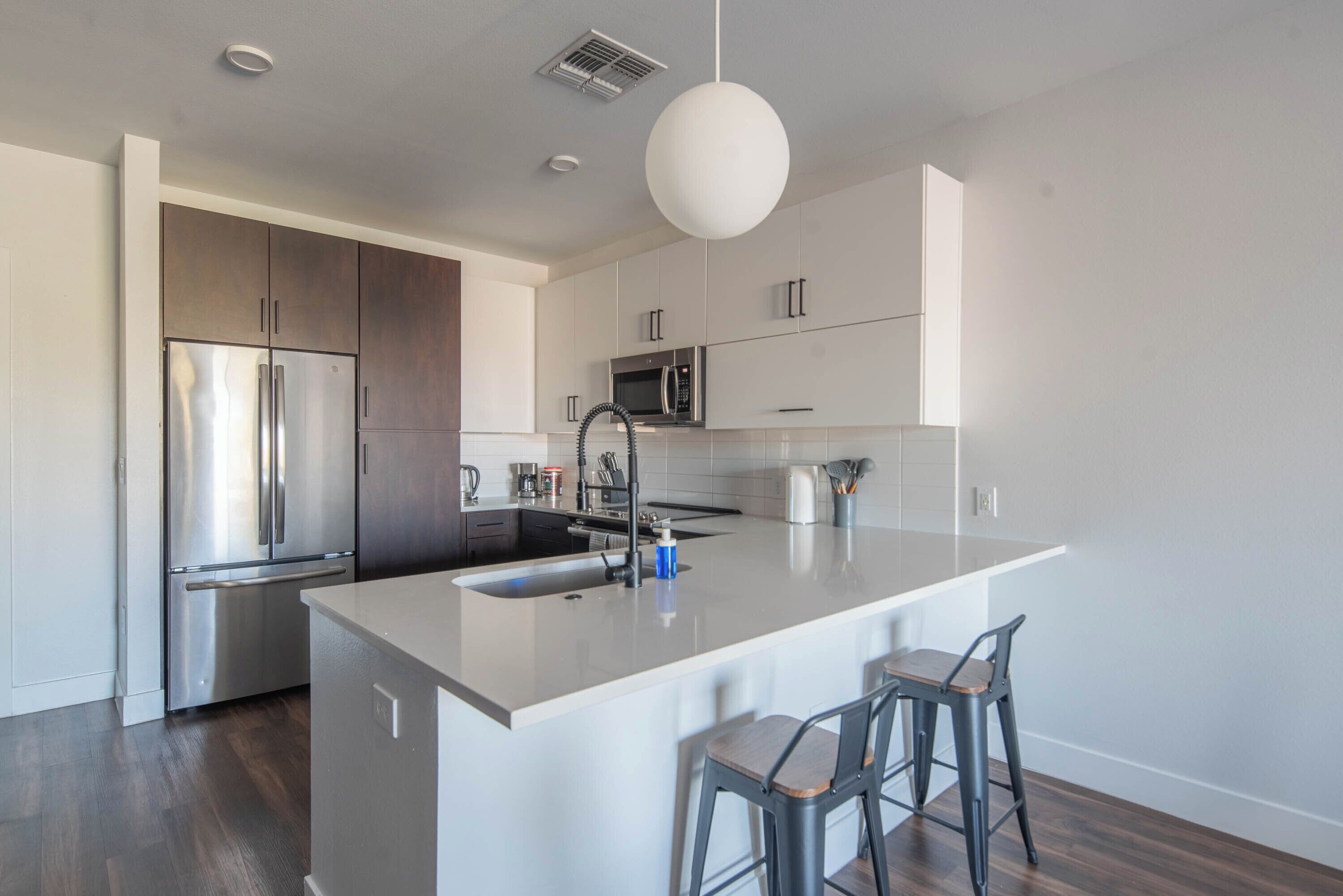 A modern kitchen with a central island, stainless steel appliances, and bar stools.