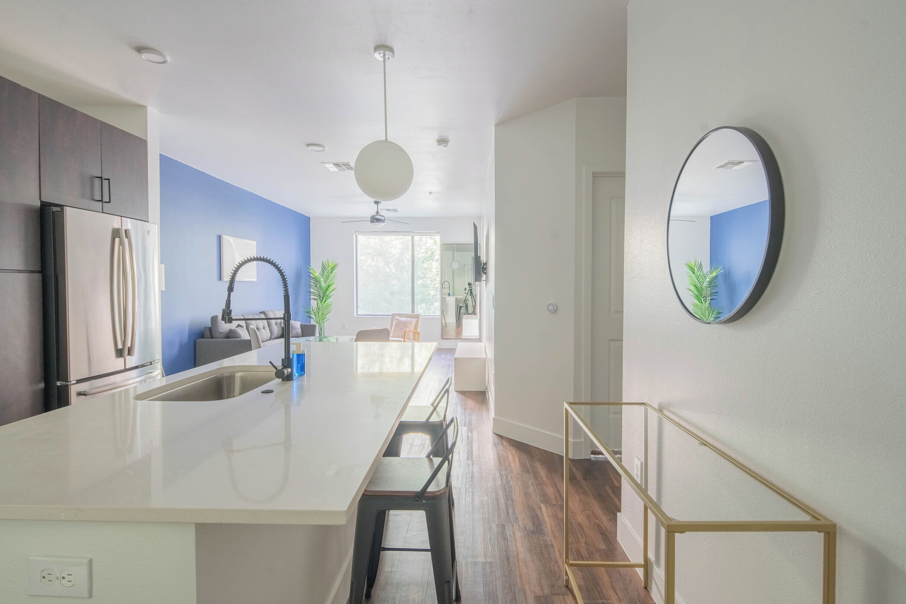 A modern kitchen with a large island, white cabinets, and a blue accent wall.