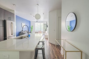 A modern kitchen with a large island, white cabinets, and a blue accent wall.