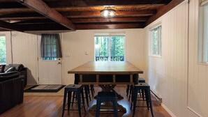 Un comedor con una gran mesa de madera, cuatro taburetes y un ventilador de techo.