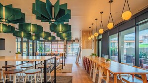 A modern dining area with high tables, bar stools, and pendant lighting. - ROVE LIVING/KB - Joy on 4th (Phoenix)