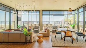 A spacious living area with a modern sofa set, a dining table with chairs, and large windows offering a city view. - ROVE LIVING/KB - Joy on 4th (Phoenix)