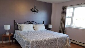 A bedroom with a large bed, two bedside lamps, a chandelier, and a window with curtains. - Full 4 bedrooms single house at Halifax Peninsula (Halifax)