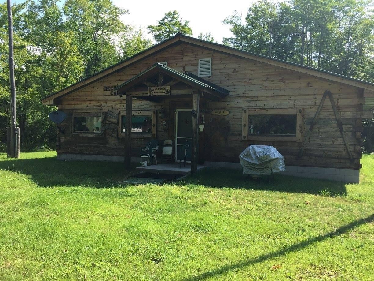 A wooden cabin with a porch, a covered front area, and a small outdoor seating area.