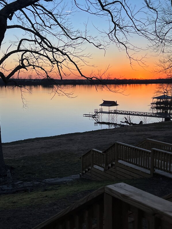 A lakeside view with a wooden dock and a traditional pavilion.