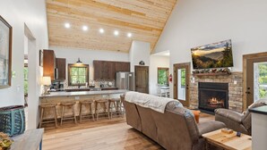 A spacious living room with a fireplace, a kitchen with wooden cabinets, and a dining area with a bar.