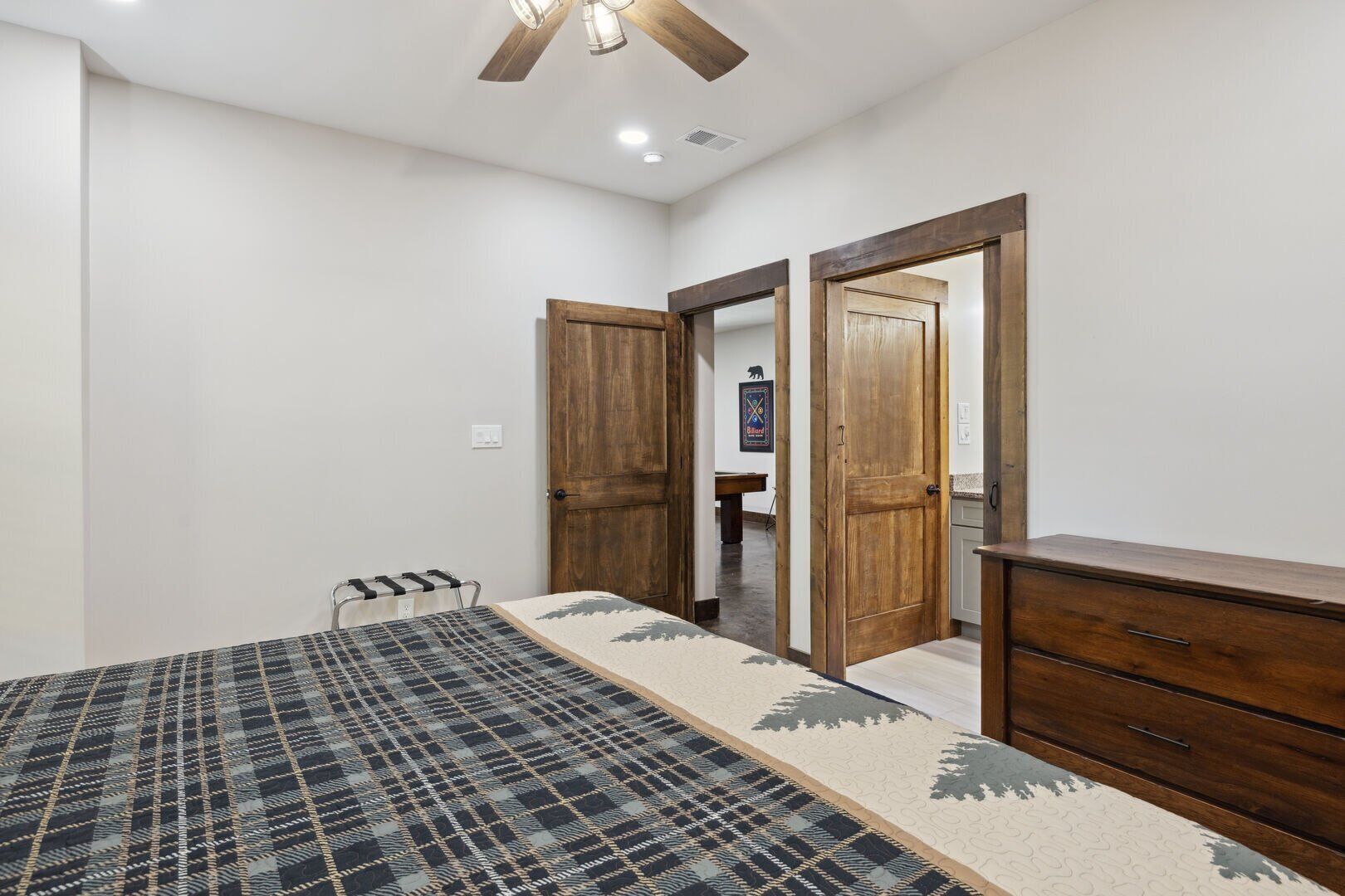 Une chambre à coucher avec un lit, une commode en bois et une porte donnant sur une autre pièce.