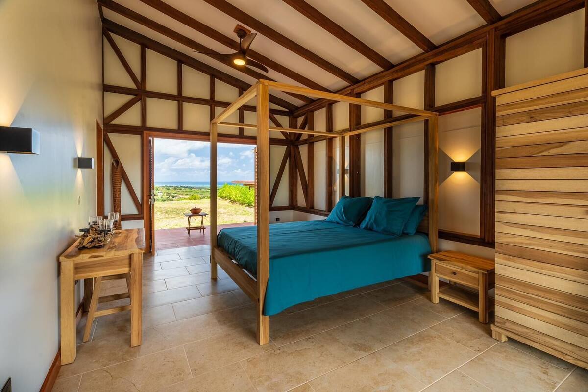 A bedroom with a four-poster bed, wooden walls, and a view of the outdoors.