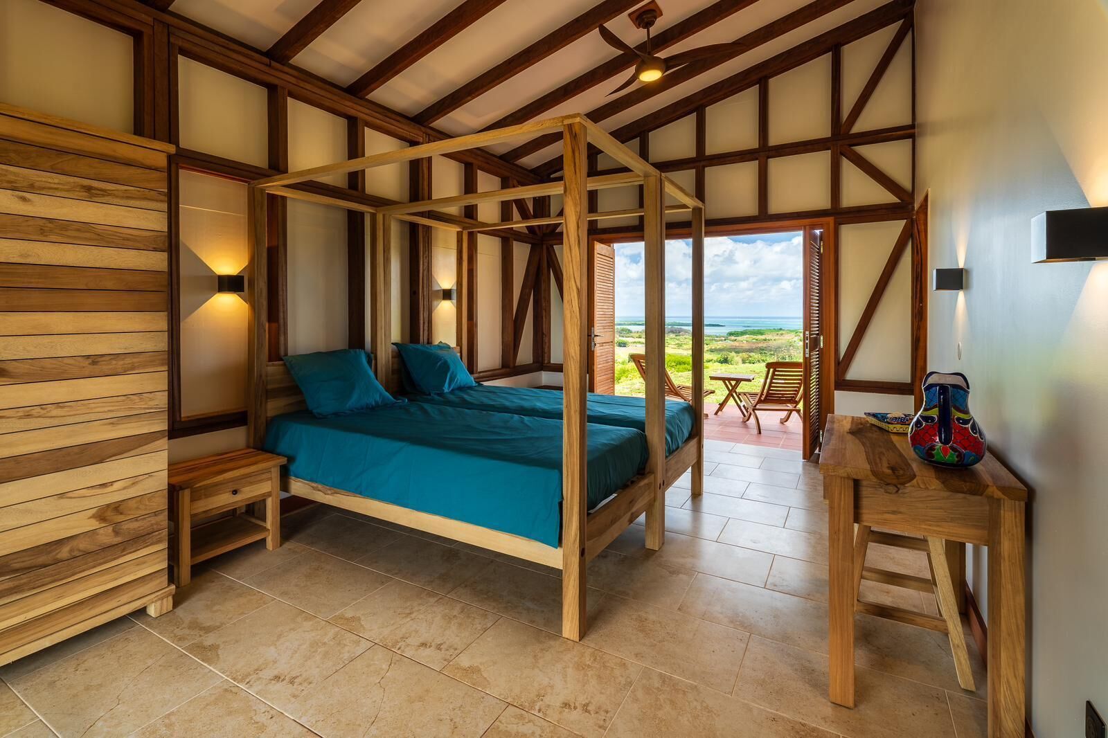 Een slaapkamer met een hemelbed, houten wanden en uitzicht op het landschap.