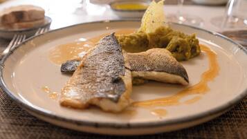 Un plato de comida con pescado y puré de papas.