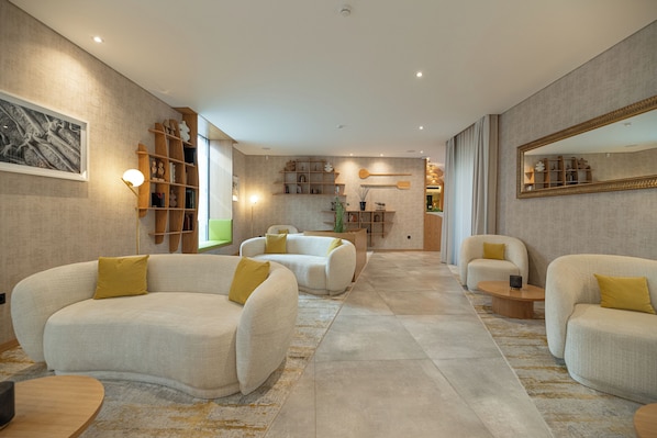 A spacious living area with modern furniture, a large mirror, and a bookshelf.
