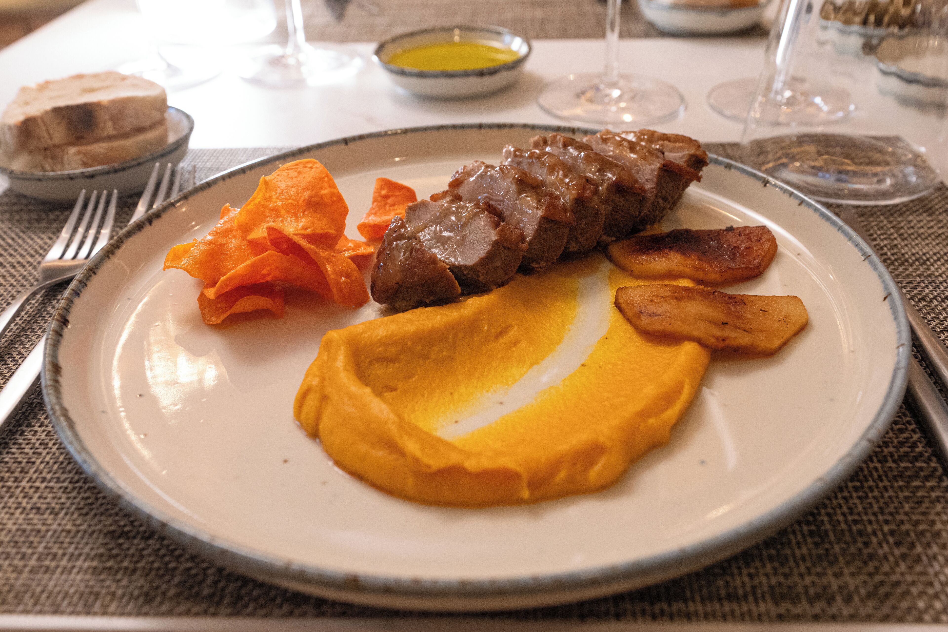 Un plato con una porción de carne, patatas asadas y puré de patatas.