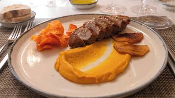 Un plato con una porción de carne, patatas asadas y puré de patatas.