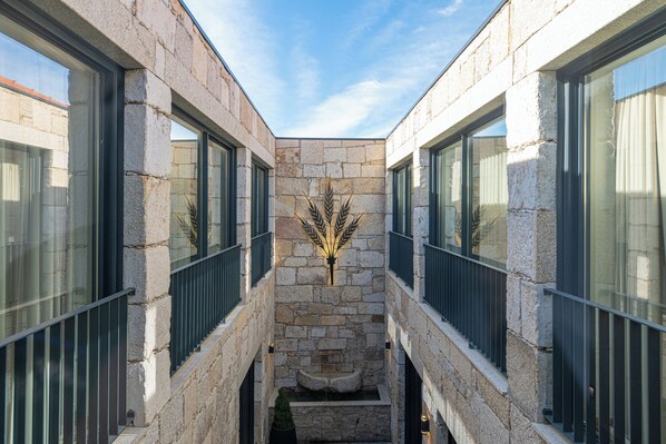 A narrow stone corridor with a central decorative element, flanked by glass windows with dark frames. - Favaios Aldeia Resort (Alijó)
