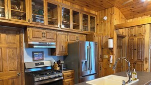 A kitchen with wooden cabinets, a stainless steel refrigerator, an oven, a sink, and a toaster.