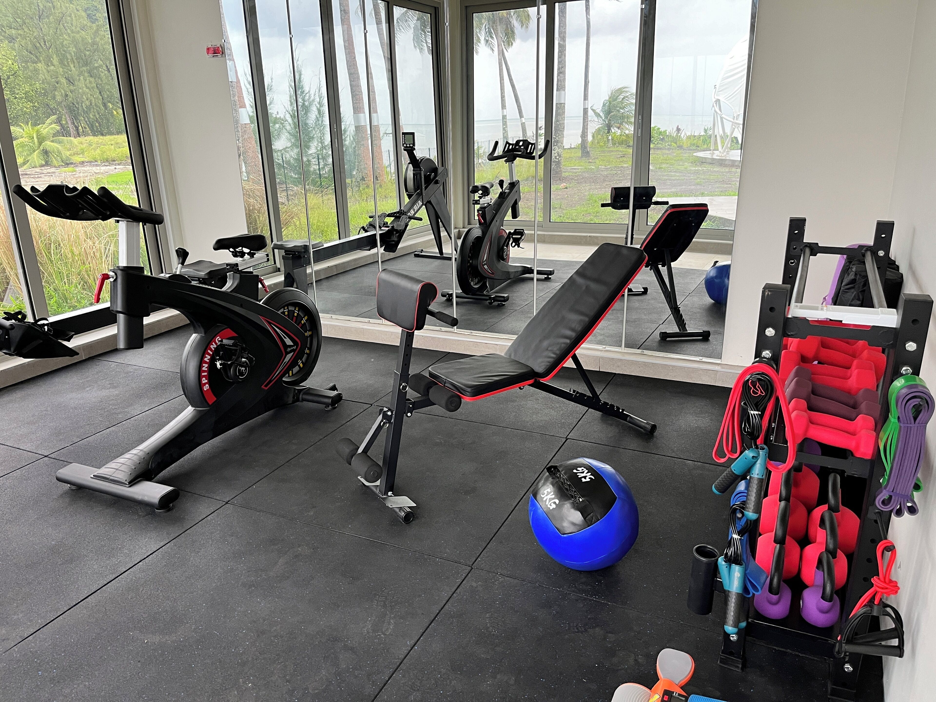Un gimnasio con equipo de ejercicio, una banca y una máquina de remo.