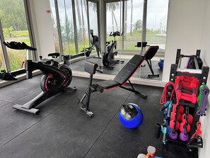 Ein Fitnessraum mit Trainingsgeräten, einer Bank und einem Rudergerät.