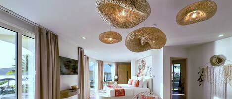 A spacious living area with a large window, a round wooden table, and a sofa with decorative pillows.