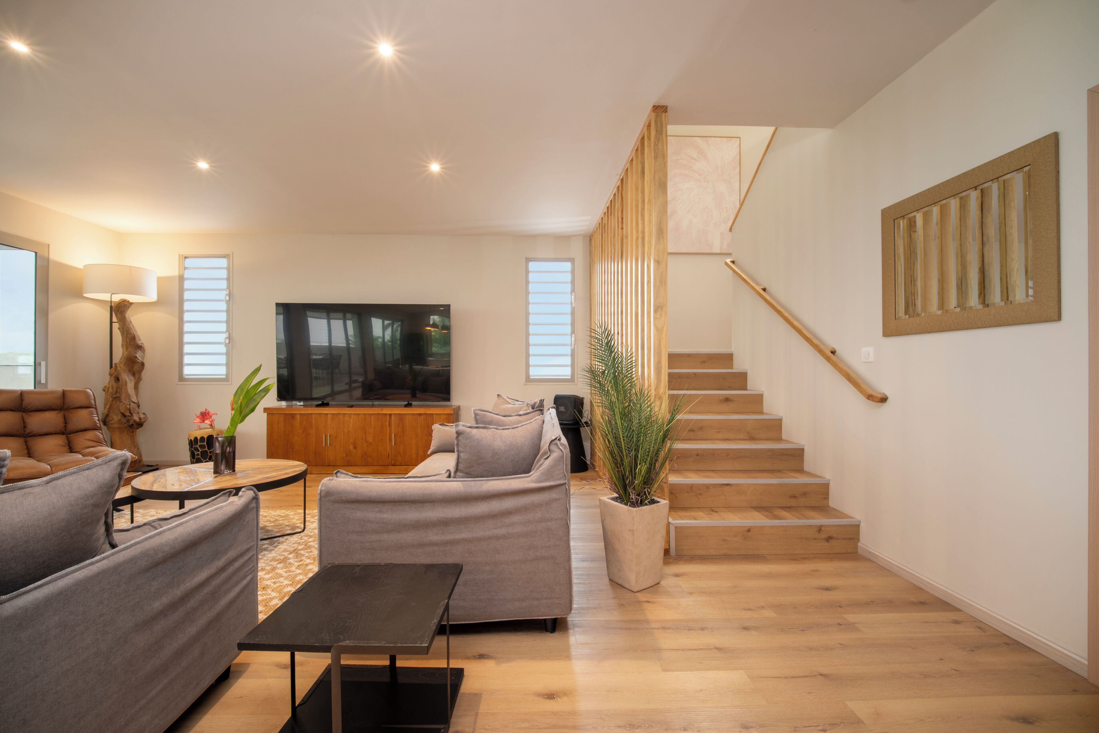 A modern living room with a sofa, coffee table, TV, and staircase.