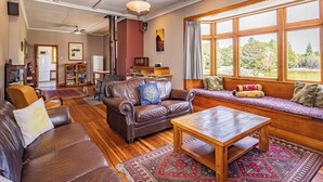 Una sala de estar acogedora con un sofá de cuero, una mesa de centro de madera y un amplio ventanal con vistas a la vegetación.