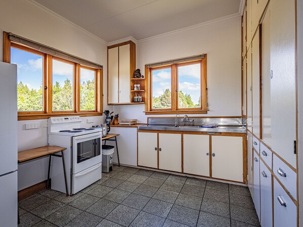 A compact kitchen with a stove, sink, and wooden cabinets. - MJ's Retreat, Stunning 20yr special with spa pool (Horopito)