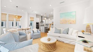 A spacious living area with a dining table, sofas, and a kitchen in the background. - OnHoliday30A by Stay on 30a (Inlet Beach)