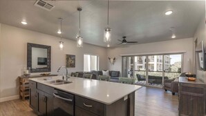 Una cocina amplia con una isla central, un área de comedor con sofá y un balcón con mobiliario exterior.
