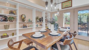 A dining area with a wooden table set for four, surrounded by white shelving units with various decorative items. - Discover Sedona Peaceful Oasis: a serene 3BR retreat with stunning Red Rock views. (Sedona)
