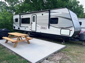 Un camping-car Coleman est garé à l’extérieur, avec une table de pique-nique devant.