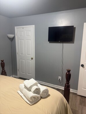 A hotel room with a bed, a flat-screen TV mounted on the wall, and a door. - Cozy three bedroom fully furnish house
(Ettrick)