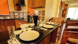Une cuisine dotée d’un îlot central, de meubles en bois et d’un coin repas avec une chaise et une table.