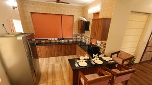 Une cuisine avec des meubles de rangement en bois, un plan de travail noir et une table à manger pour quatre personnes.