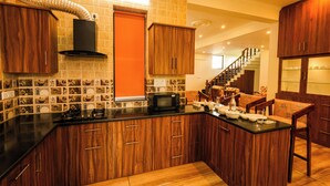 Une cuisine avec des meubles en bois, un plan de travail noir et un four à micro-ondes. Un escalier mène à un autre niveau.