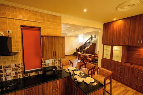 A modern kitchen with a black countertop, wooden cabinets, and a red door.