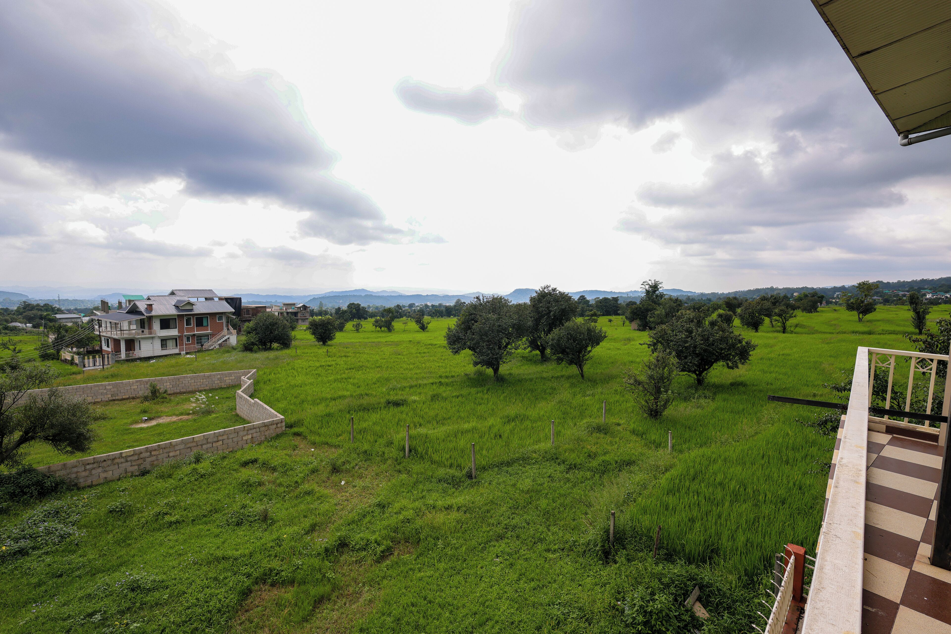 A residential area with a house, green field, and distant mountains.