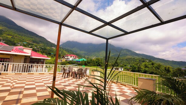 Une terrasse à carreaux offrant une vue sur les montagnes et une maison avec un toit rouge.