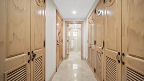 Corredor com portas de madeira e chão de azulejos, dando acesso a um banheiro.