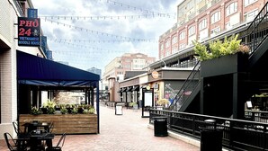 A cobblestone street with outdoor seating and string lights, surrounded by buildings with commercial establishments. -  Stylish loft, centered in the heart of Atlantic station. (Atlanta)
