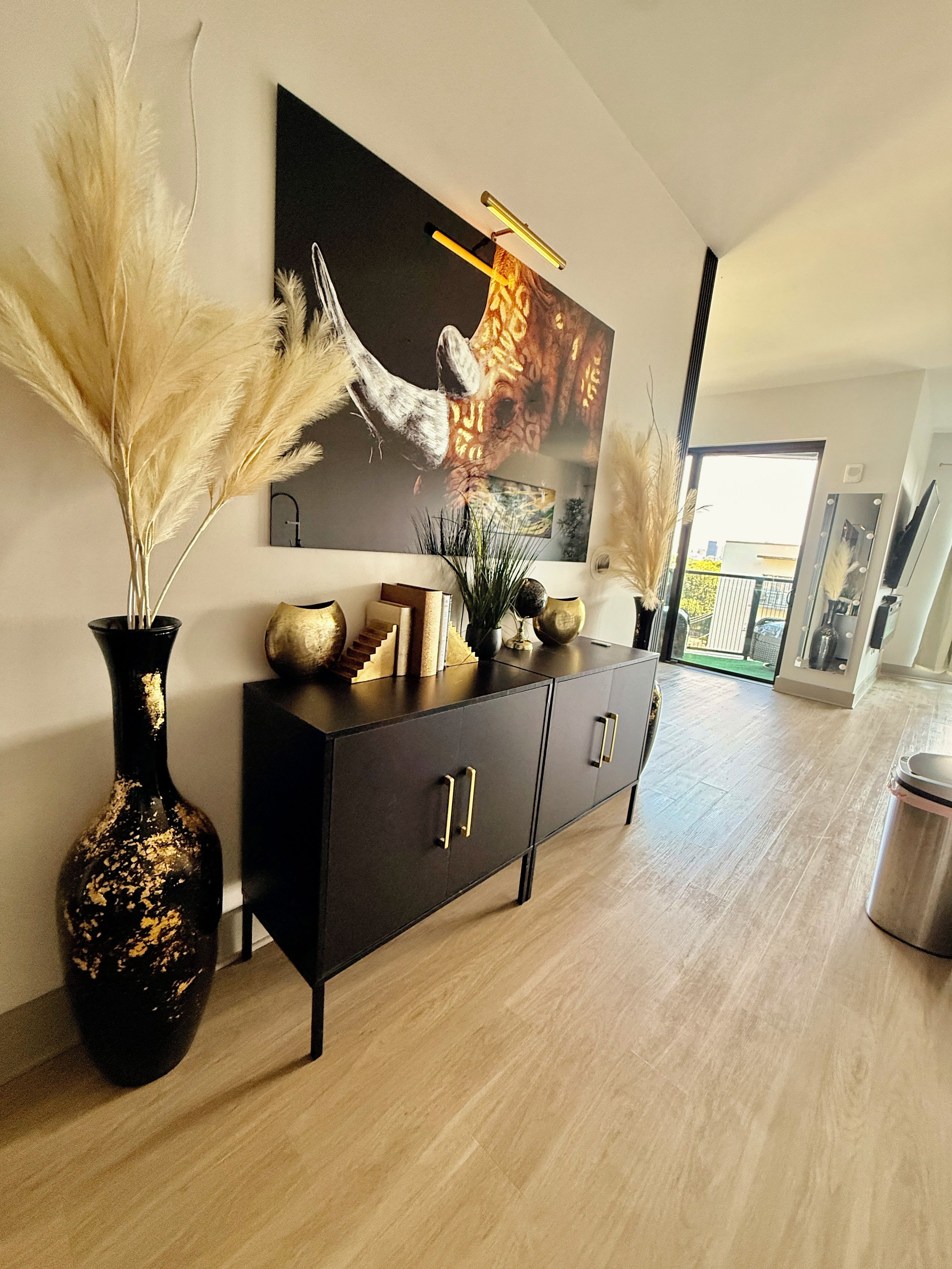 A modern interior with a black console table, decorative items, and a large framed picture on the wall.