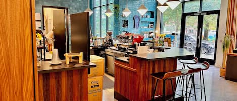 A modern kitchen area with a bar counter, wooden accents, and hanging pendant lights.