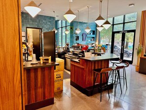 A modern kitchen area with a bar counter, wooden accents, and hanging pendant lights.