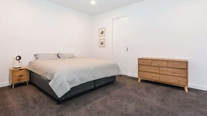 A bedroom with a bed, bedside table, and a dresser.