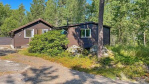 A cabin with a front porch, a small deck, and a surrounding wooded area. - 3 bedroom awesome home in Ljusterö (Ljusterö)
