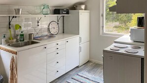 A modern kitchen with white cabinets, a stainless steel sink, a microwave, and a stove. There is a window providing natural light and a view of greenery outside. - 3 bedroom awesome home in Ljusterö (Ljusterö)