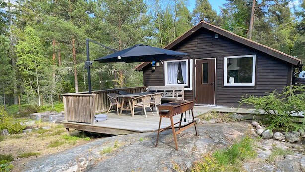 A cabin with a deck, outdoor furniture, and a large umbrella. - 3 bedroom awesome home in Ljusterö (Ljusterö)