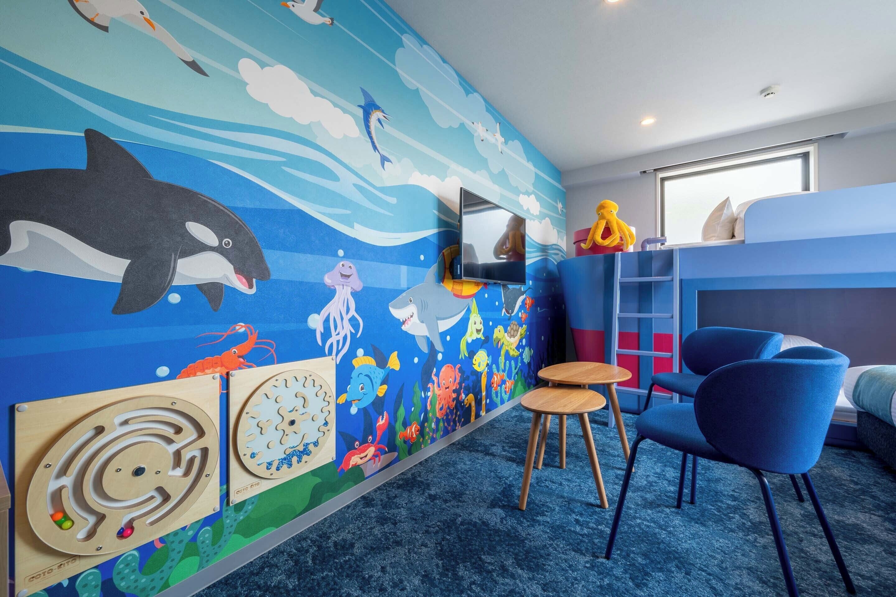 A children's room with a mural of ocean creatures, a bunk bed, a TV, and modern furniture.