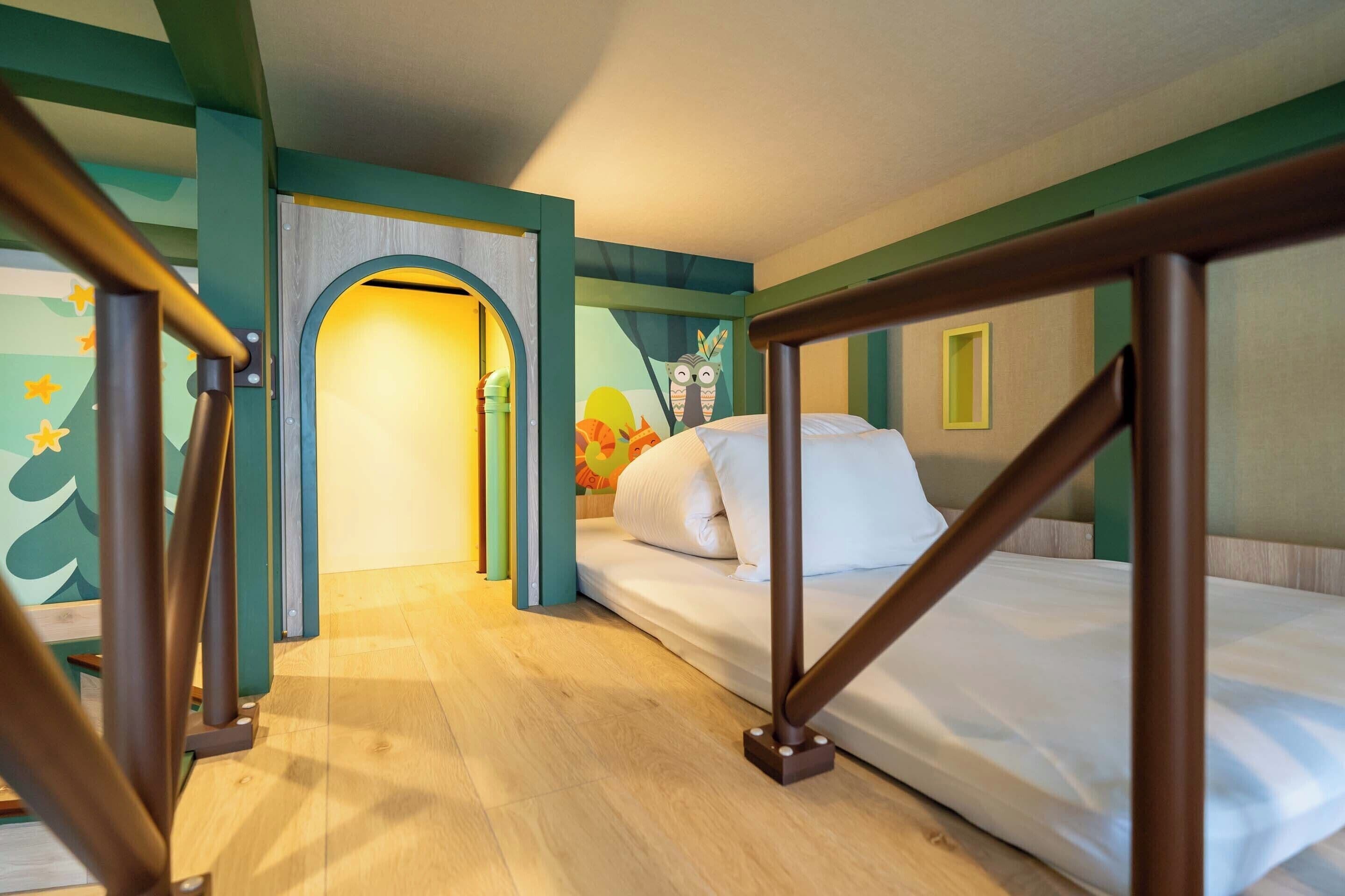 A child's room with a bed, a wooden frame, a door with a circular window, and a wall with a colorful mural.