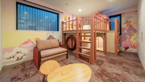 A children's playroom with bunk beds, a sofa, and a small table.
