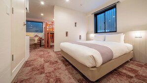 A bedroom with a large bed, a window, and a desk area.