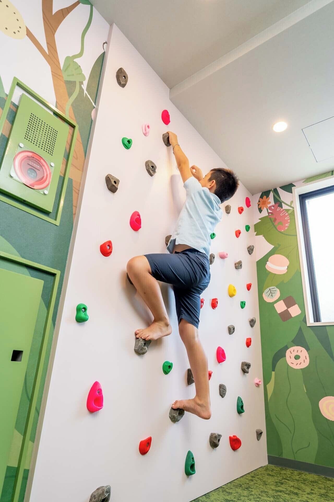 A person climbing a wall with colorful handholds.
